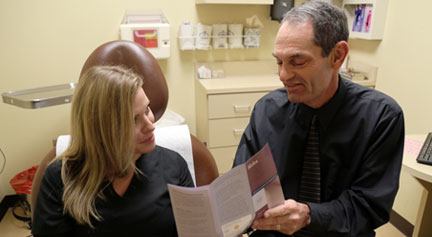 Board certified dermatologist, Dr. Alan Parks, gives information to a patient